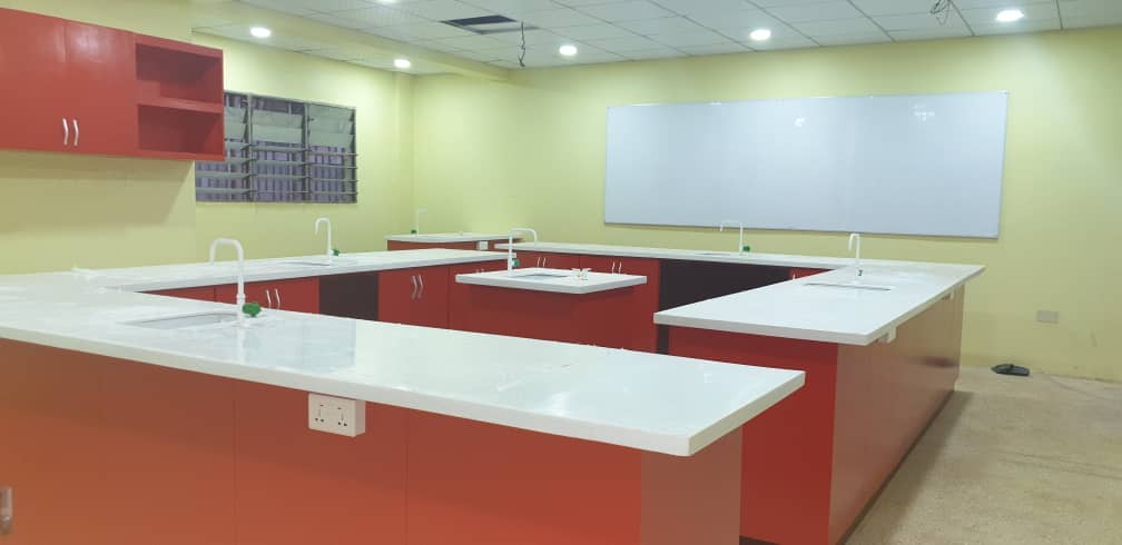Completed Aspire International School science laboratory with red benches, sinks, service taps, and whiteboard