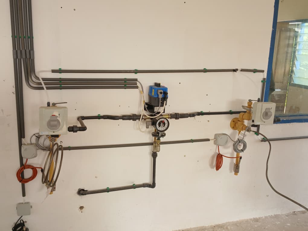 Wall-mounted water control line installation at Sekyere Hemmang with gauge, dosing control, and service piping
